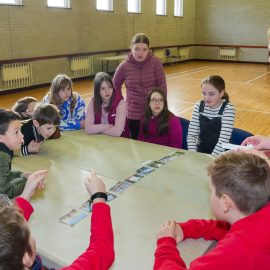 Children sitting around a table with a Sunday School leader asking questions.